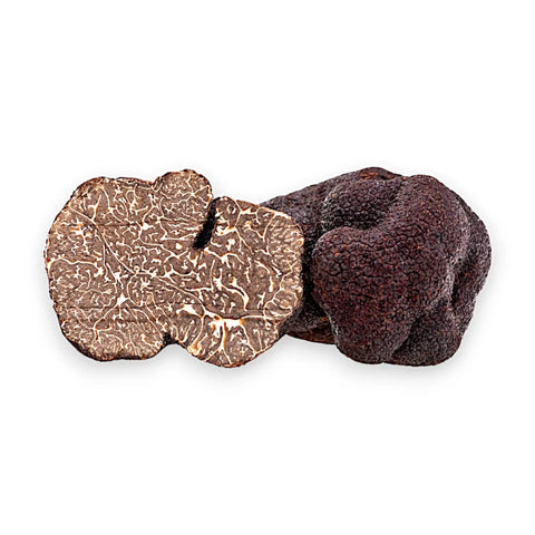 Whole and cut Tuber melanosporum Black Truffles showing the dark marbled interior